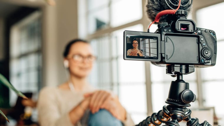 woman filming a video of herself with a DSLR camera